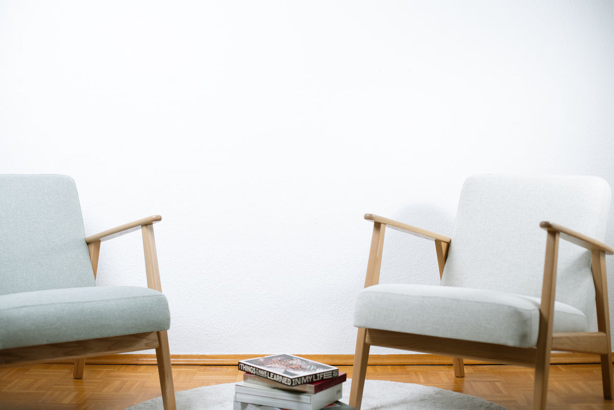 Wohnzimmer mit zwei hellgrauen Sesseln und leerer weißer Wand vor der Begrünung – Raum vor der Gestaltung im Urban Jungle Stil